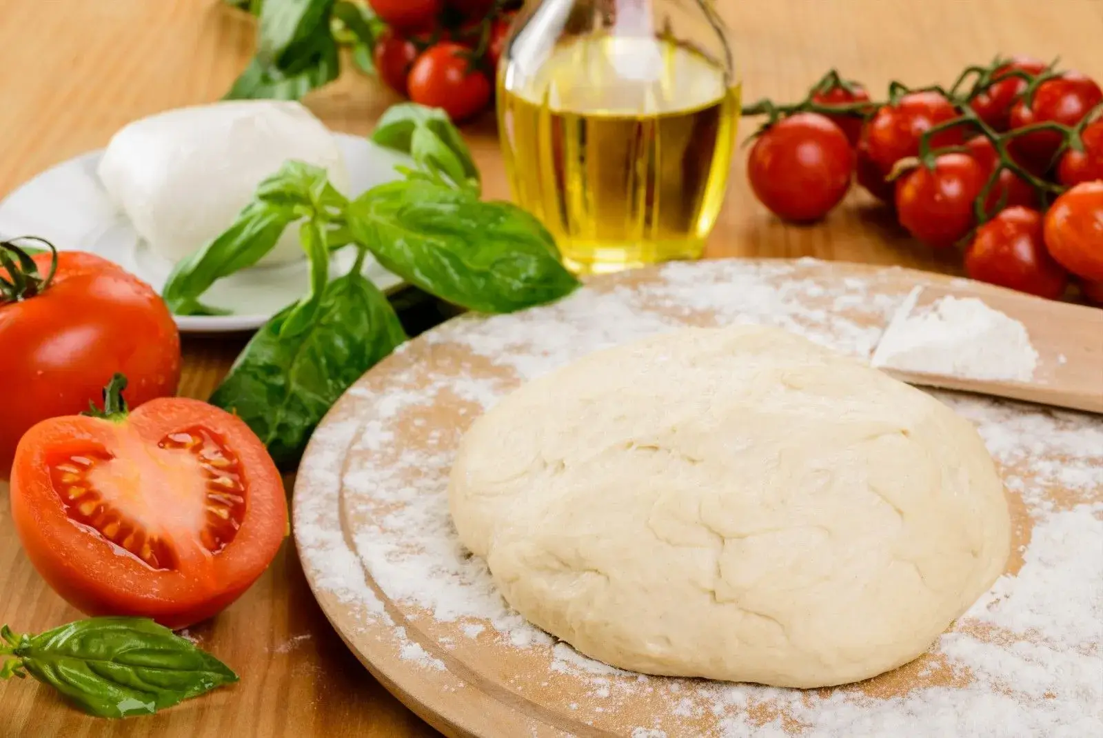 Fresh, raw pizza ingredients like dough, tomatoes, and basil.